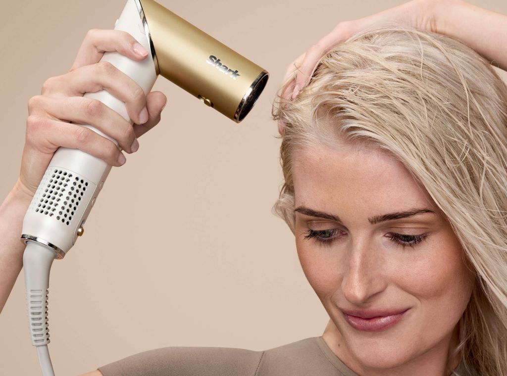 Woman using a Shark hair dryer, showing professional hair styling at home