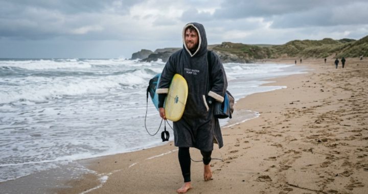 Surfer wearing a fleece-lined surf poncho on a cold beach after a morning surf session