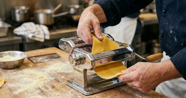 Stainless steel pasta maker on a bright modern kitchen countertop.