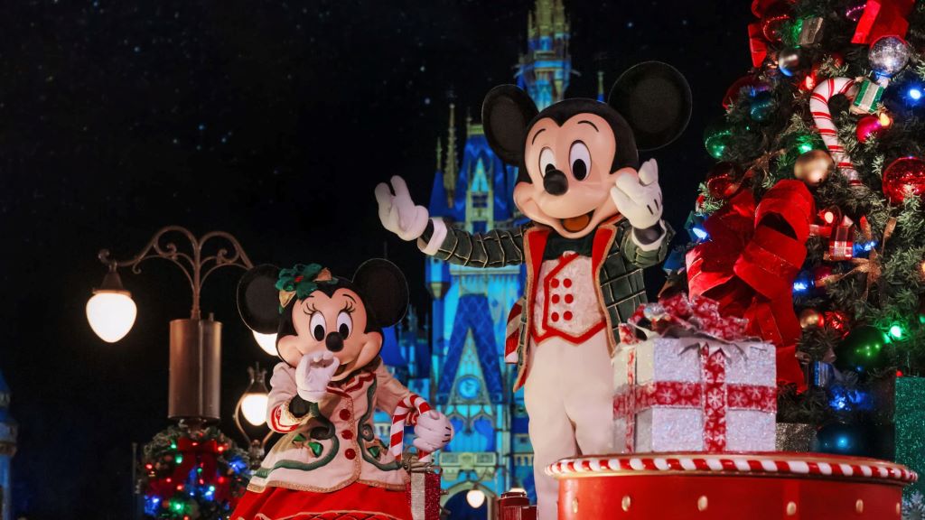 Mickey and Minnie Mouse waving from a festive float during Mickey's Once Upon a Christmastime Parade at Magic Kingdom